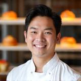 Professional headshot of David, Pastry Chef, smiling with baked goods in background