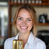 Professional headshot of Emma, Workshop Leader, holding a coffee tamper